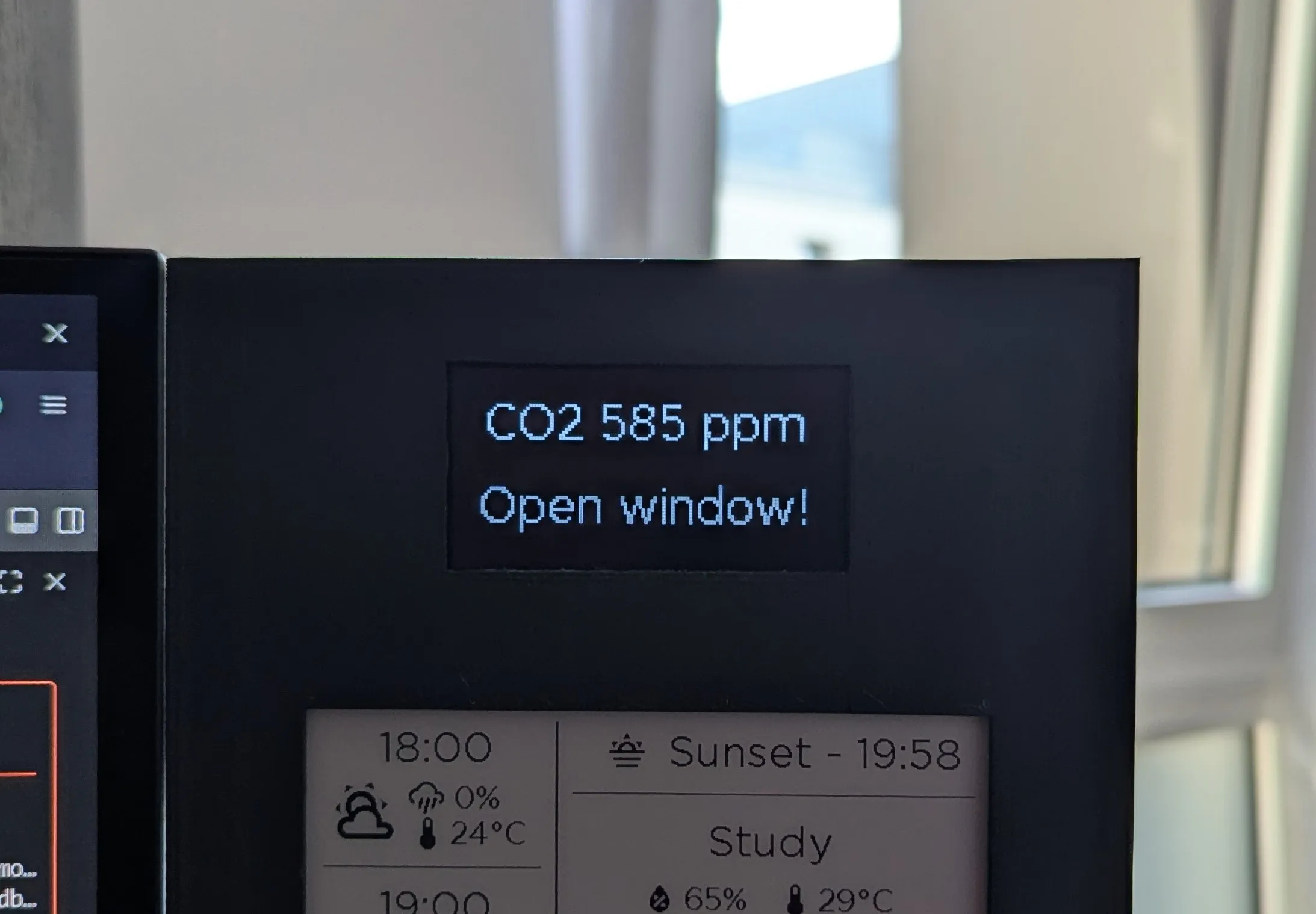 Photograph of the OLED display with the notification text "CO2 585 ppm Open window!"